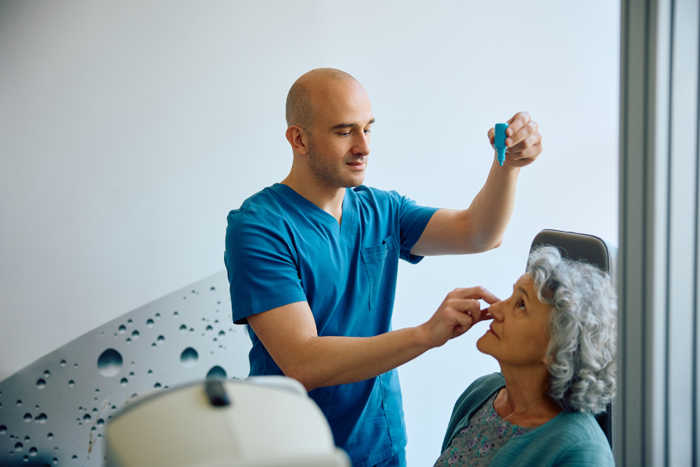 Senior woman receiving eye drops from a doctor in a clinical setting.