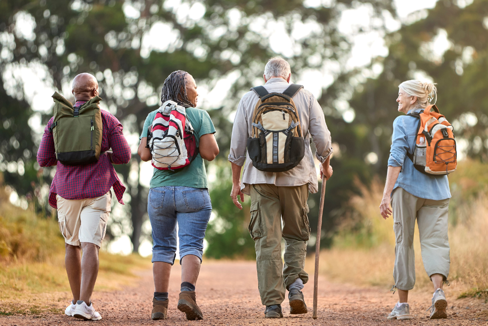 Rear view of senior friends hiking on a trail with backpacks