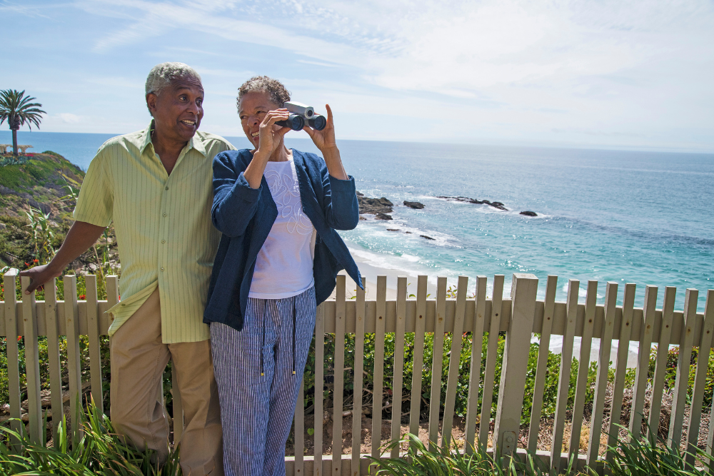 Senior couple enjoying a scenic ocean view with binoculars.