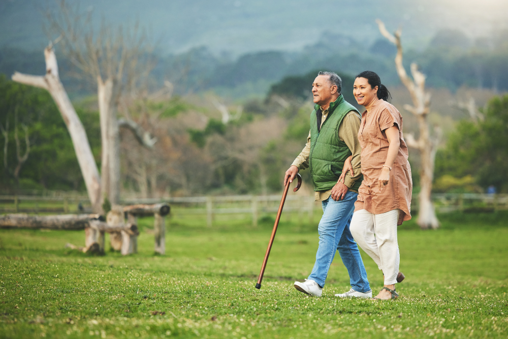 Senior couple walking together in a park, the man using a cane.