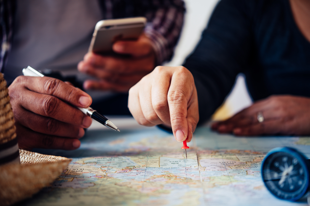 Close-up of hands planning a trip with a map and a smartphone.