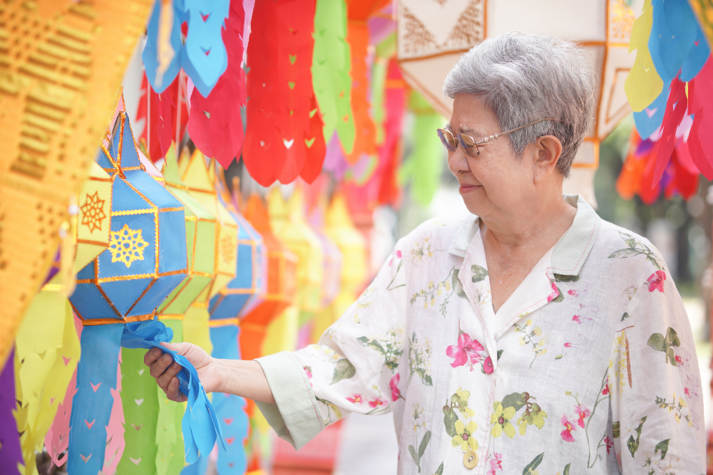 Elderly woman admiring colorful hanging decorations.