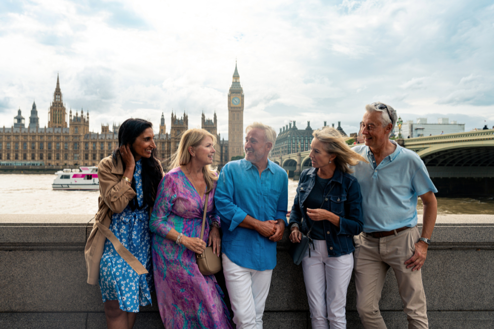 A group of five seniors enjoying a day out in London with the iconic Big Ben and the Houses of Parliament in the background.