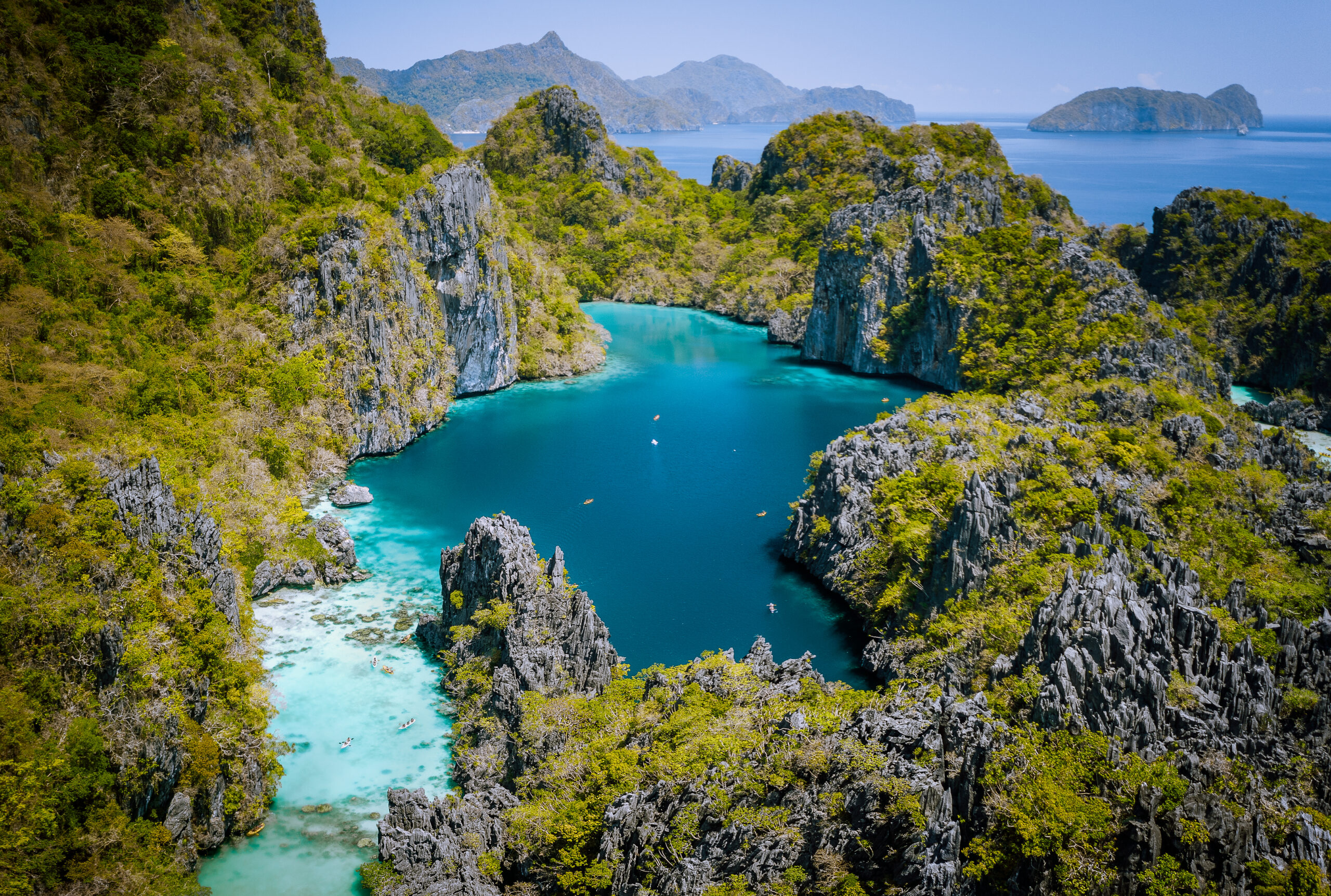 Aerial view of a turquoise lagoon surrounded by rocky cliffs and lush greenery in El Nido, Palawan.